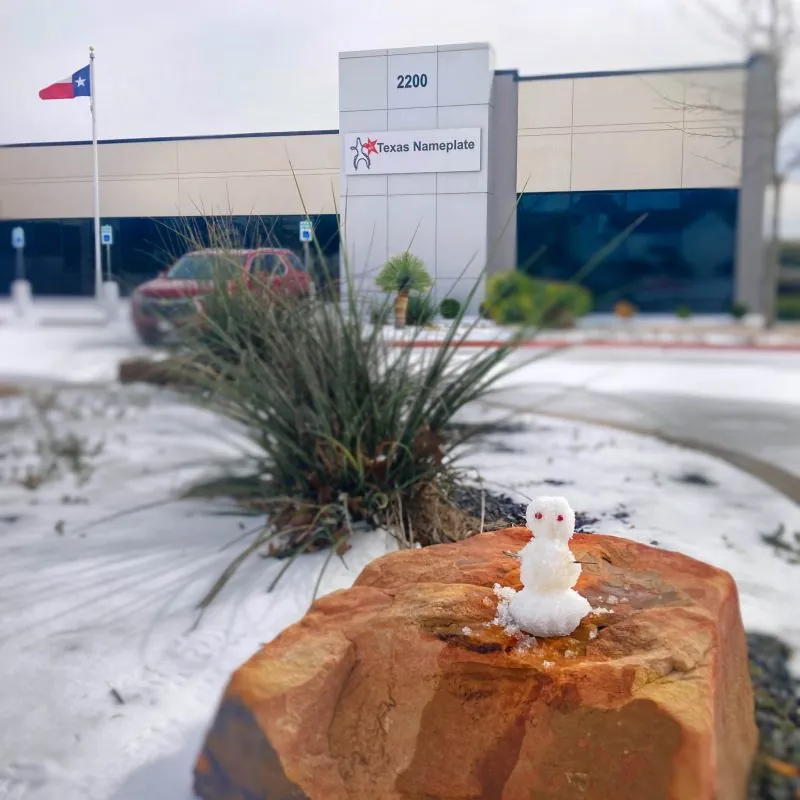 A tiny snowman on a rock outside the Texas Nameplate building