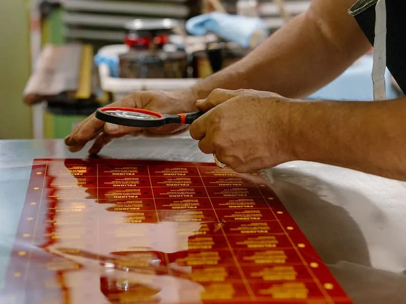 A craftsman checking a printed label sheet under a magnifier