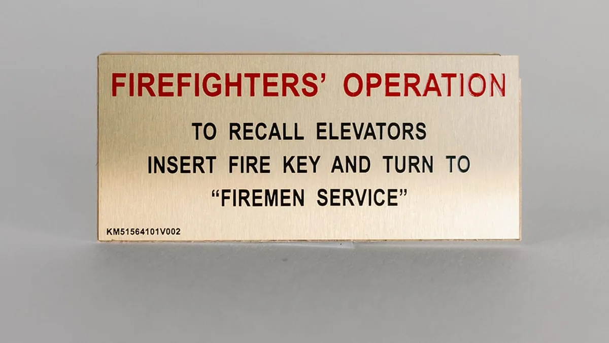 A brass Firefighters' Operation elevator recall instruction plate