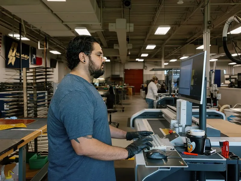 An operator at the cutting-table console on the production floor