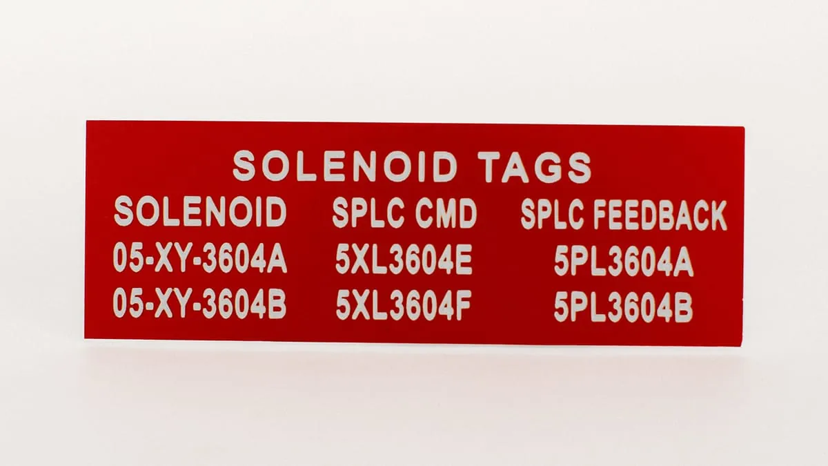 A red two-color phenolic solenoid tag panel with engraved circuit designations