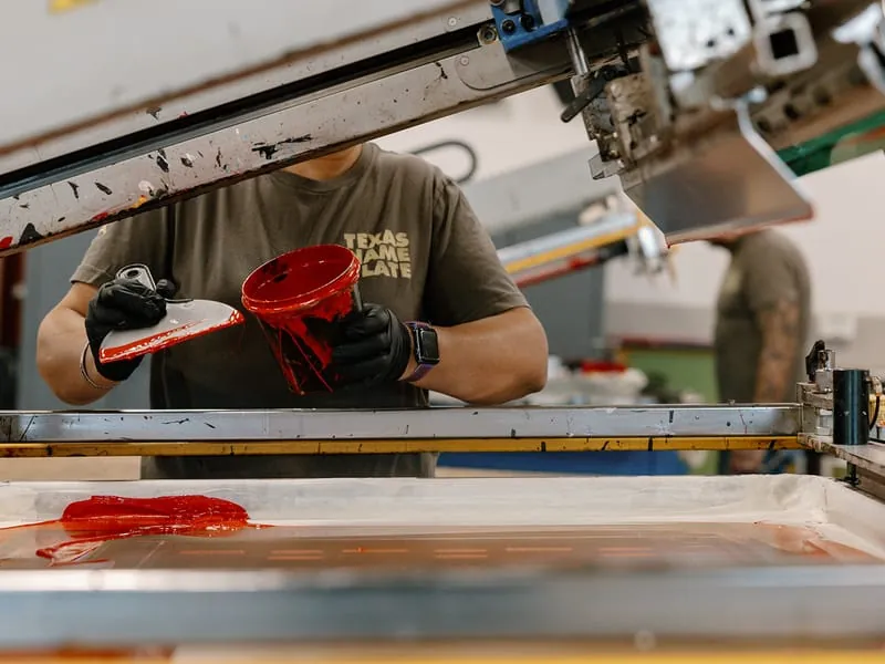 Red ink being poured onto a press screen