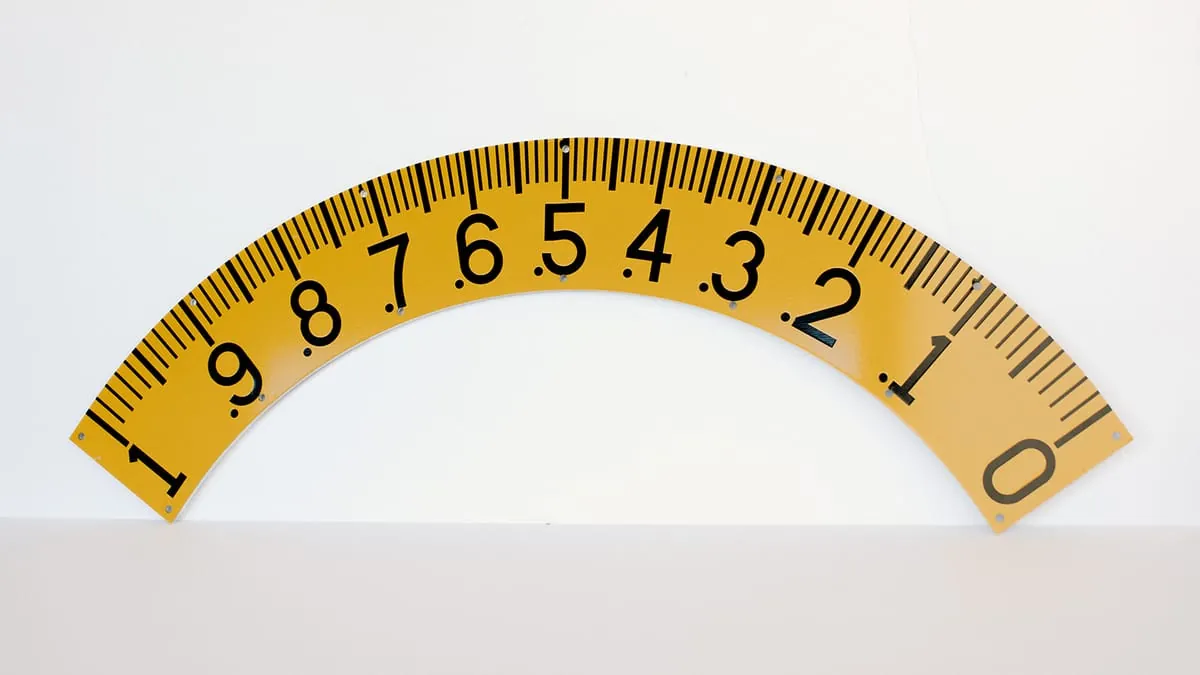 A curved yellow measuring scale with etched graduations and numbering