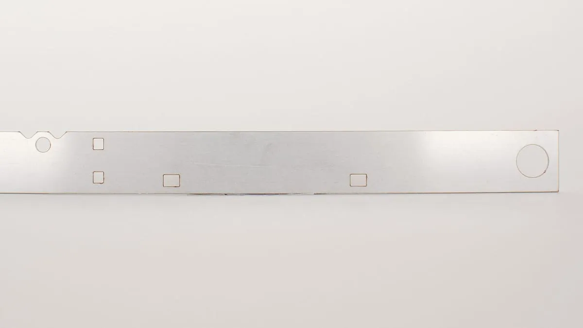 A long thin aluminum tag strip with punched mounting holes